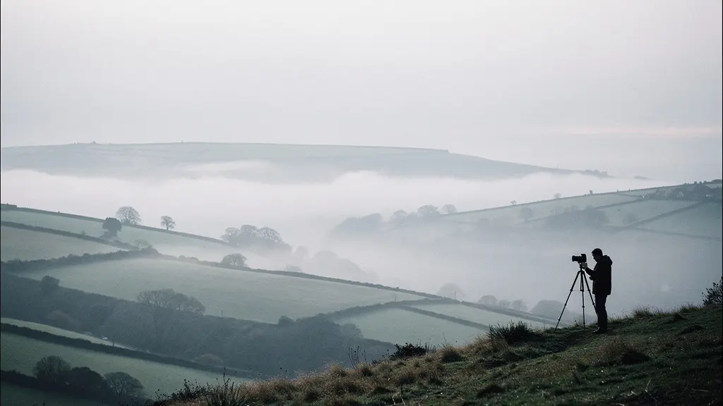 Photographer capturing misty landscape in overcast British weather conditions