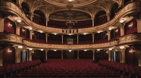 Grand Victorian West End theatre interior showcasing ornate golden balconies and plush red velvet seating